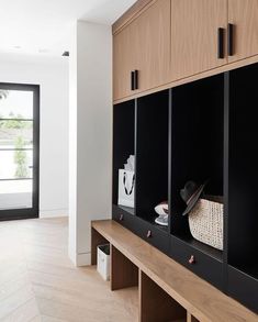 an empty room with wooden cabinets and black doors, along with a white basket on the wall