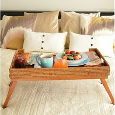 a tray with fruit, juice and coffee on it sitting on top of a bed