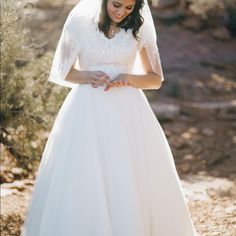 a woman in a white wedding dress and veil looking down at her hands on her chest