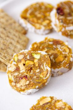 some crackers are sitting on a plate with nuts and other food items around them