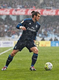 a soccer player is about to kick the ball during a game in the rain,