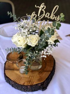 a vase filled with white flowers sitting on top of a wooden slice