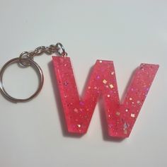 the letter w is made up of pink glitters and has a metal keychain