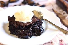 a piece of chocolate cake on a white plate with a spoon and whipped cream in it