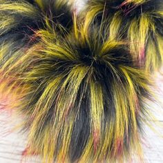 a close up of a furry object on a white surface with red, yellow and black streaks