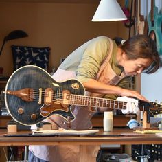 a woman working on a guitar in her workshop