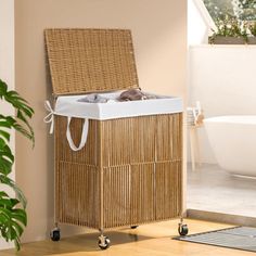 a wicker laundry hamper sitting on wheels next to a bathtub