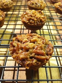 several muffins cooling on a wire rack in the sun with some toppings