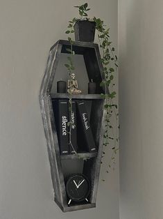 a clock hanging from the side of a wall next to a potted plant on top of a shelf