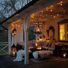 an outdoor living area with lights strung from the ceiling and couches on the deck