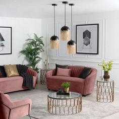 a living room with pink couches and two tables in front of paintings on the wall