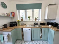 a small kitchen with blue cabinets and white appliances, including a dishwasher on the counter