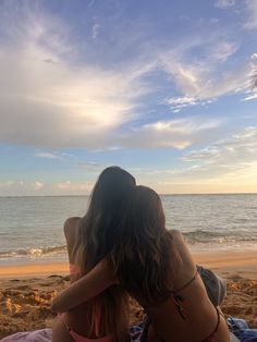 two women sitting on the beach with their backs to each other