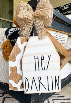 a wooden sign that says hey darlin on the side of a bed in front of a house