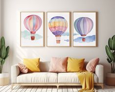 three hot air balloons are hanging on the wall next to a couch in a living room