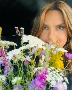 the woman is holding a bouquet of flowers in her hand and looking at the camera