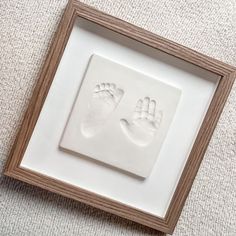 a white frame with two hand and foot prints on the wall next to a carpet