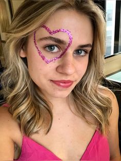 a girl with pink glitter heart drawn on her face