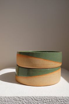 two green and yellow bowls sitting on top of a white countertop next to each other