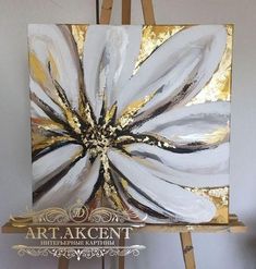 an easel with a painting on it that has gold and white flowers painted on it