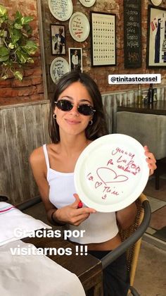 a woman holding a white plate with writing on it