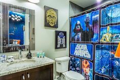 a star wars themed bathroom with pictures on the shower curtain and toilet seat cover in it