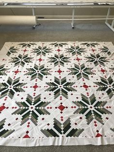 a quilt is laying on the floor in front of a table with a laptop computer