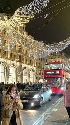 people are walking down the street in front of buildings with christmas lights strung across them