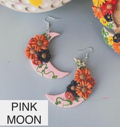 Celebrate in style with these gorgeous floral crescent moon earrings. Handmade from polymer clay. Finished with your choice of silver or gold stainless steel fish hooks or 5mm ball posts (hypoallergenic and nickel and lead free).  Jump rings will match this color choice. Four styles to choose from -  PINK MOON: gorgeous orange and black flowers on a pink crescent moon with wiggly green vines and leaves in the background. rough length from top of ear wire to bottom of charm is 3 1/4 inch rough width (at its widest) is 1 3/4inch GREEN MOON: gorgeous orange, rust, yellow, and black flowers on an olive lime green crescent moon and background. rough length (top of ear wire to bottom of charm): 2 3/4 inch rough width (at its widest): 1 1/2 inch PEARL MOON: gorgeous orange, rust, yellow, and blac Pink Bohemian Resin Jewelry, Bohemian Pink Resin Jewelry, Nickel Free Flower Polymer Clay Jewelry, Nickel-free Polymer Clay Flower Jewelry, Whimsical Polymer Clay Flower Jewelry, Whimsical Flower-shaped Polymer Clay Jewelry, Handmade Crescent Resin Jewelry, Bohemian Polymer Clay Round Jewelry, Bohemian Round Polymer Clay Jewelry