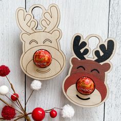 two wooden reindeer head ornaments on top of a white wood table next to red and white balls