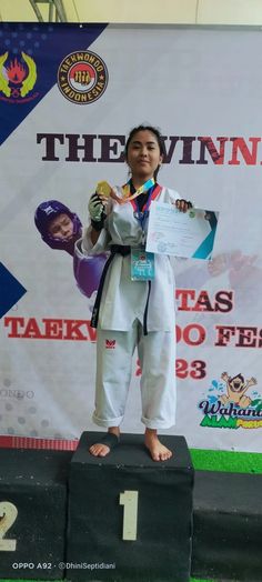 a woman standing on top of a podium holding a medal