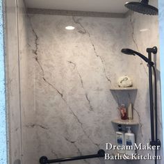 a bathroom with marble walls and flooring in the shower area, including an overhead hand shower head