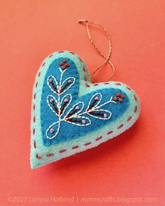 a blue and red heart ornament on a pink background