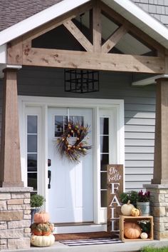 a front porch decorated for fall with pumpkins and gourds