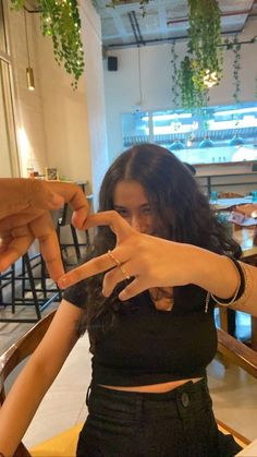 a woman sitting at a table with her fingers in the shape of a peace sign