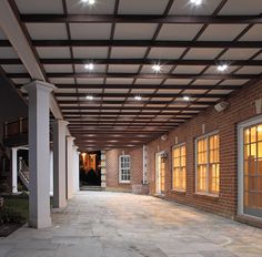 an empty patio with lights on the ceiling and brick building in the backround