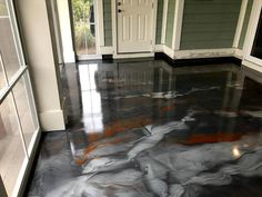 a room with black and white marble flooring in front of two doors, one door open to the other side