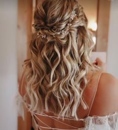 the back of a woman's head with wavy hair and pearls in her hair