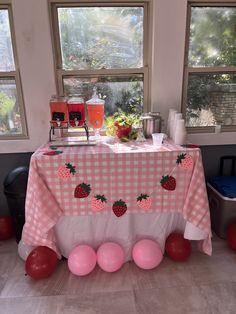 a table set up for a party with strawberries on the table and balloons around it