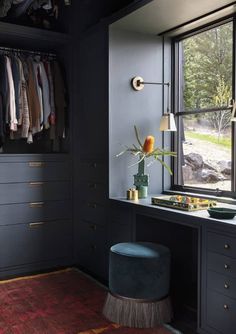 a room with black cabinets and drawers, a blue stool and a green plant in the corner