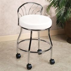 a white stool with wheels on it in front of a potted plant and wall