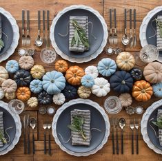 the table is set with pumpkins, silverware and other decorative items on it