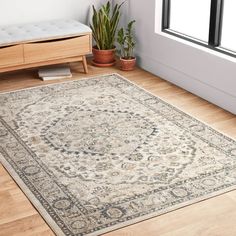 a large area rug in the corner of a room with wooden floors and potted plants