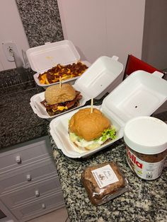 there are three takeout containers with sandwiches in them on the kitchen counter next to an ice cream container