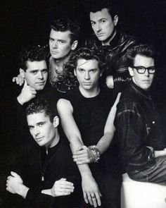 a group of young men posing for a photo in front of a black and white background