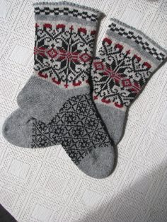 two gray and red socks sitting on top of a white table next to each other