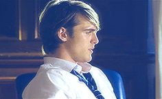 a man in a white shirt and tie sitting at a desk with a laptop computer