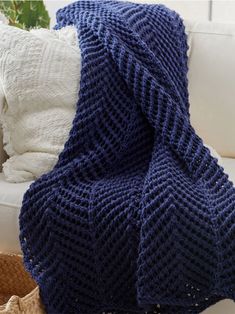 a blue knitted blanket sitting on top of a white couch