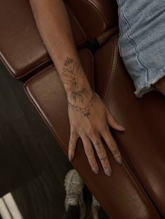 a woman's arm with tattoos on it and her hand resting on the back of a chair