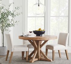 a dining room table with two chairs and a bowl of fruit on the table next to it